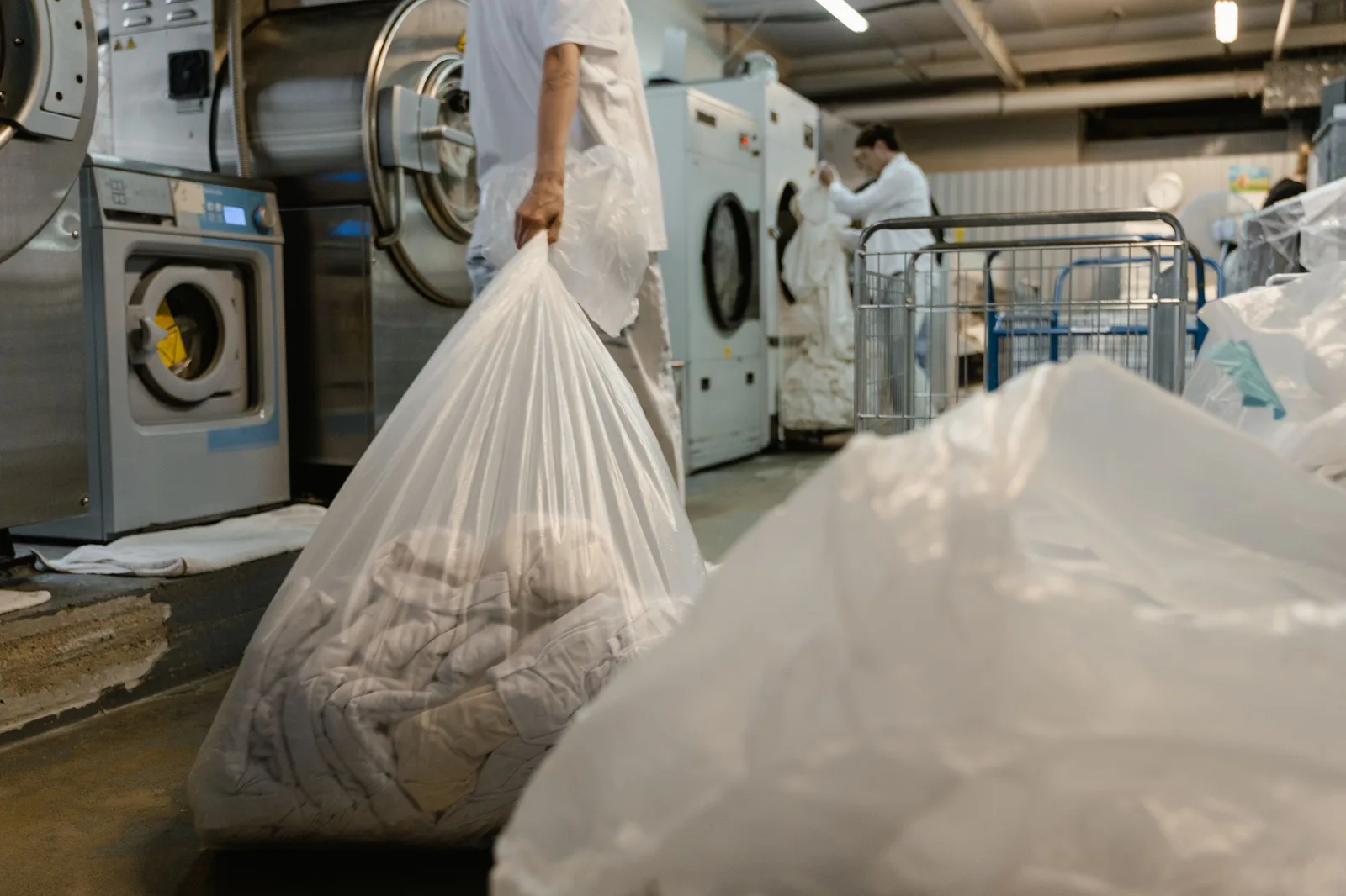 Person carrying laundry bag in a commercial laundry facility. Photo by Tima Miroshnichenko on Pexels