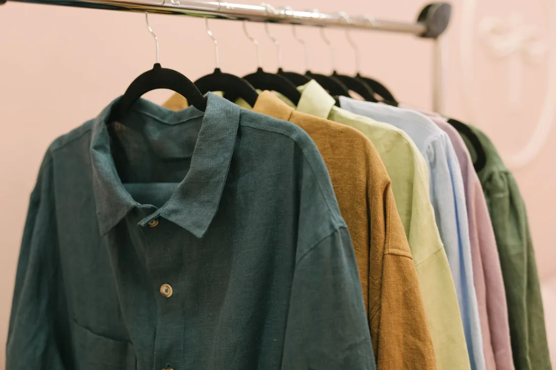 Neatly pressed shirts in muted colors hanging in a row on a rail. Photo by Thirdman on Pexels