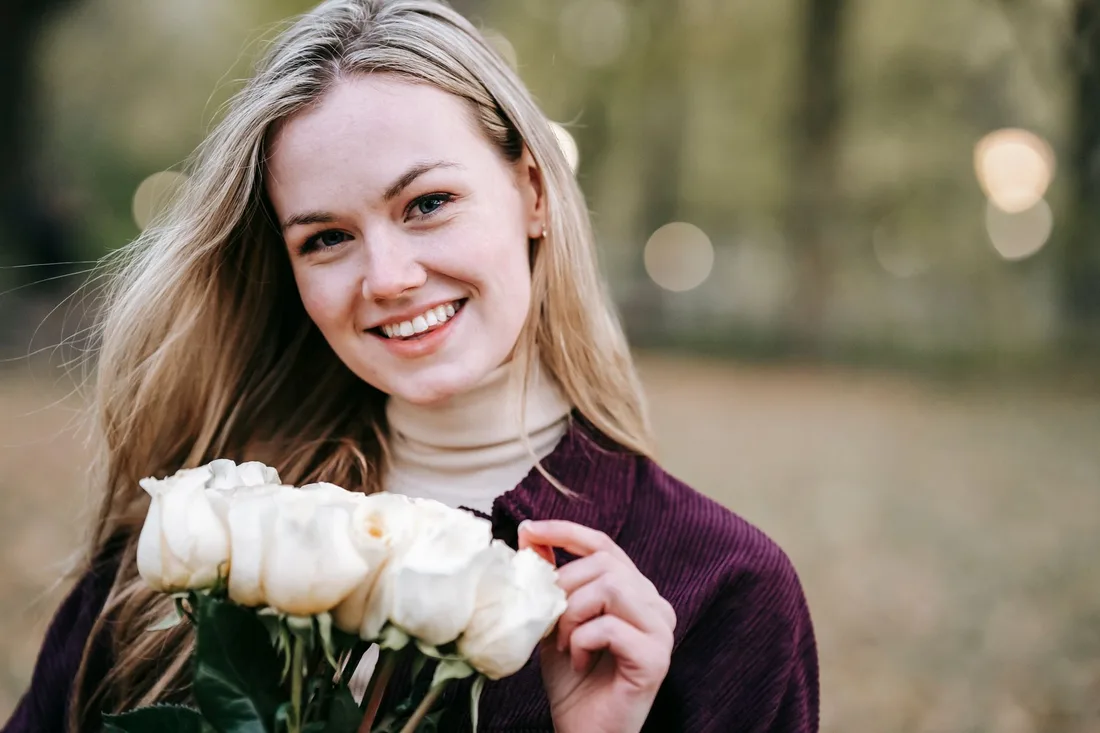 Smiling woman holding a bouquet of white roses. Photo by Katerina Holmes on Pexels