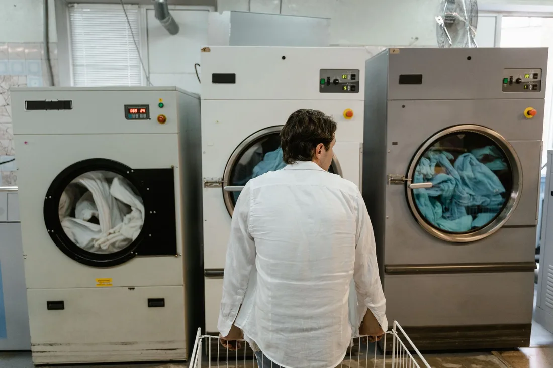 A man uses commercial washing machines at an indoor laundromat. Photo by Tima Miroshnichenko on Pexels
