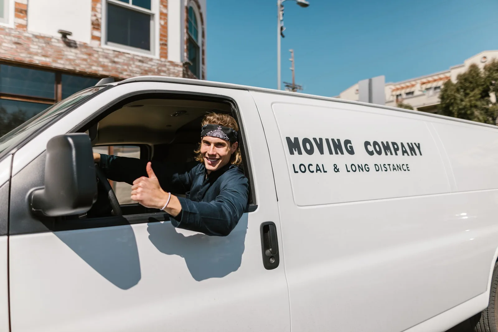 Smiling mover giving thumbs up from a moving company van parked outside. Photo by RDNE Stock project on Pexels