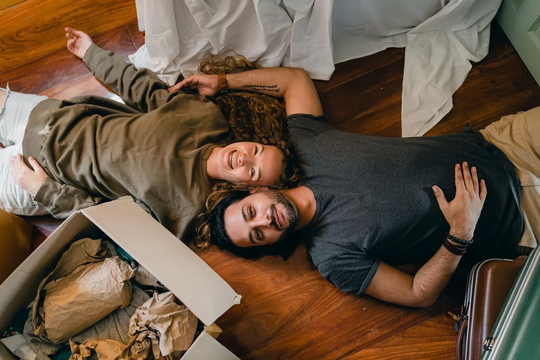 Happy couple lying on the floor of their new home among moving boxes. Photo by Ketut Subiyanto on Pexels