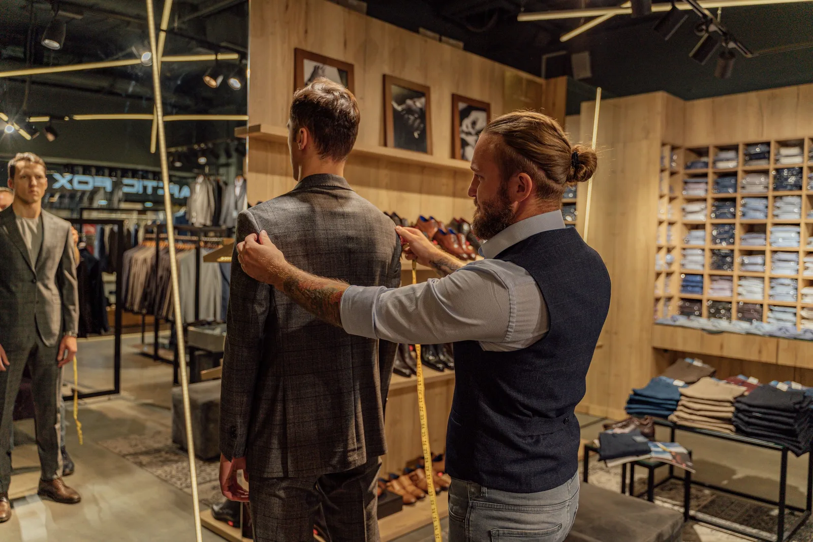 Tailor measuring a client for a suit in a stylish clothing store environment. Photo by AI25.Studio  Studio on Pexels
