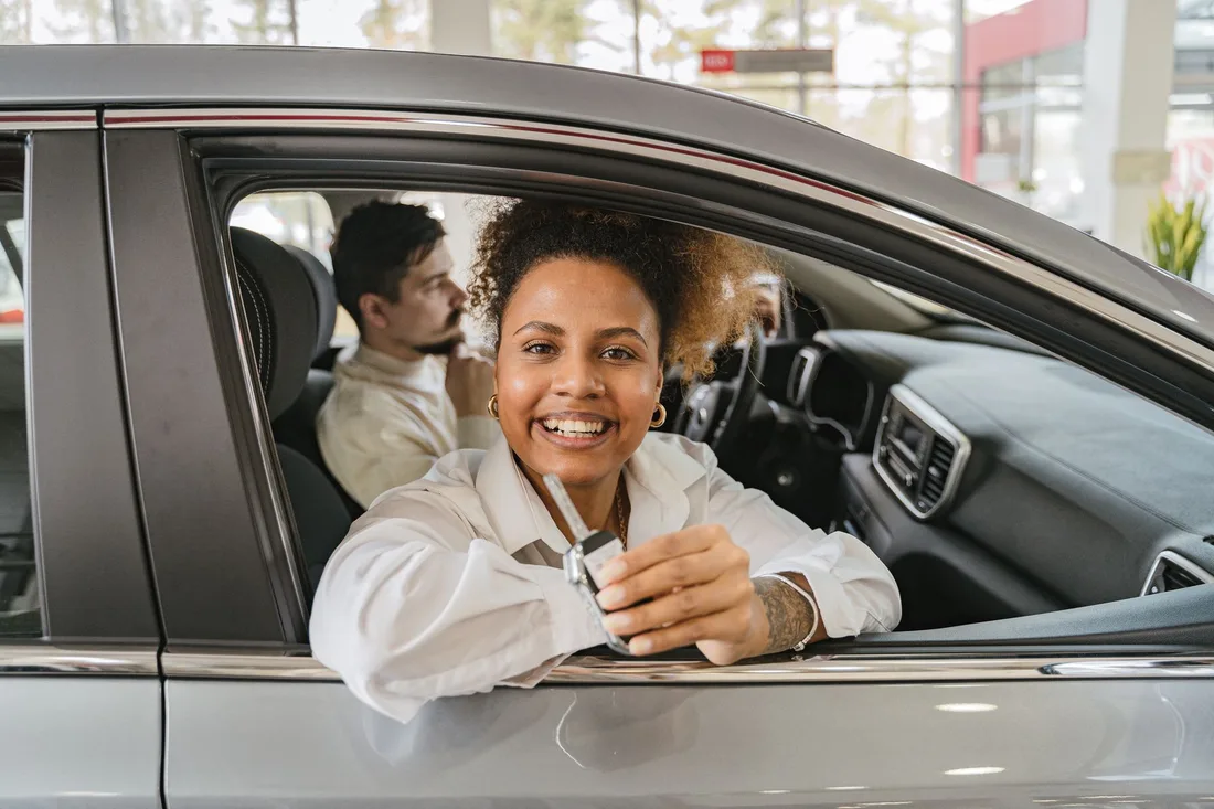 Smiling woman sitting in her car with the door window open. Photo by Antoni Shkraba on Pexels