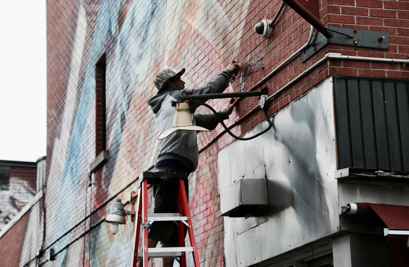 Technician on a ladder mounting a security camera on a building. Photo by Léa Claisse on Pexels