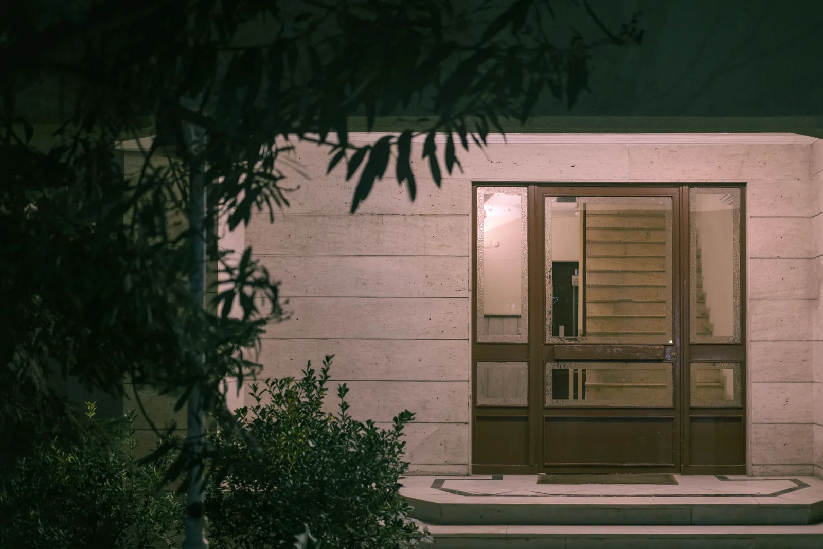 House front door lit at night with a warm glow from inside. Photo by Yusuf Çelik on Pexels