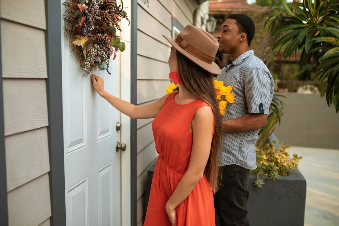 Woman in an orange dress and man pressing the doorbell at a front door. Photo by RDNE Stock project on Pexels