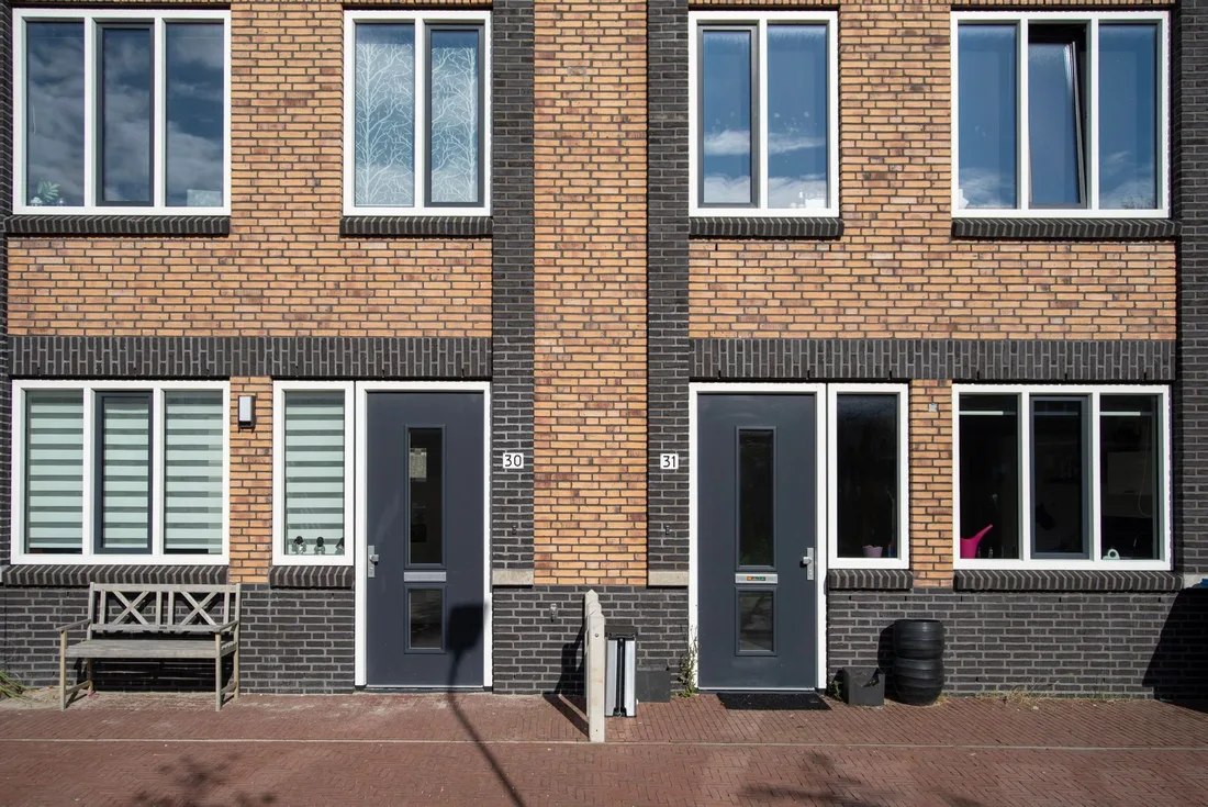 Brick townhouses with sturdy dark grey front doors and white window frames. Photo by Jan van der Wolf on Pexels