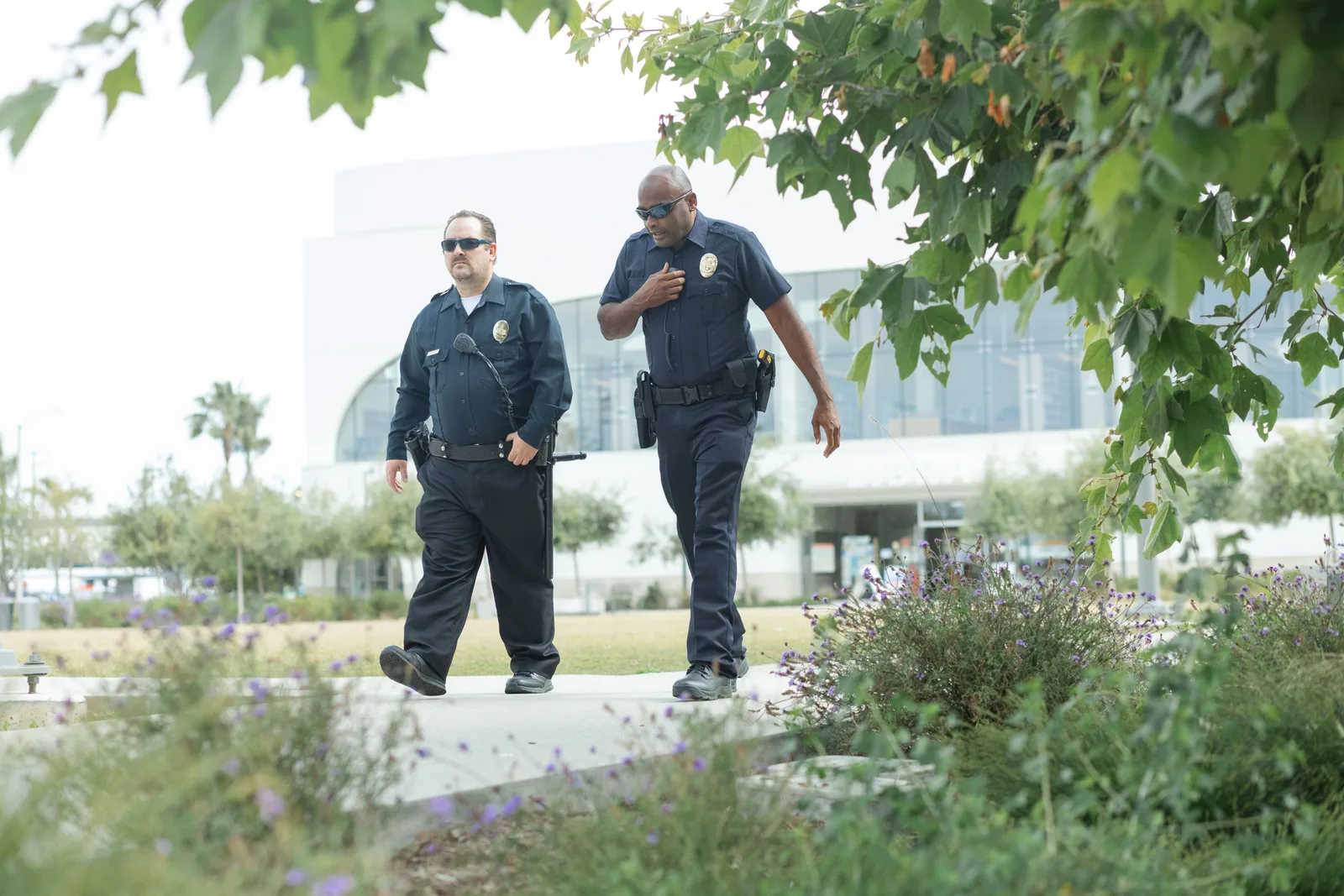 Two uniformed security guards walking a patrol outdoors on a campus. Photo by Kindel Media on Pexels