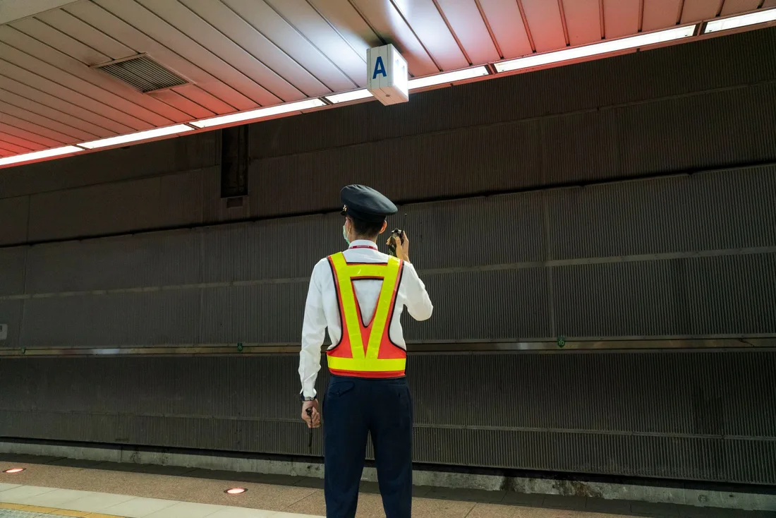 Security officer in a hi-vis vest standing guard on a covered walkway. Photo by Jimmy Liao on Pexels