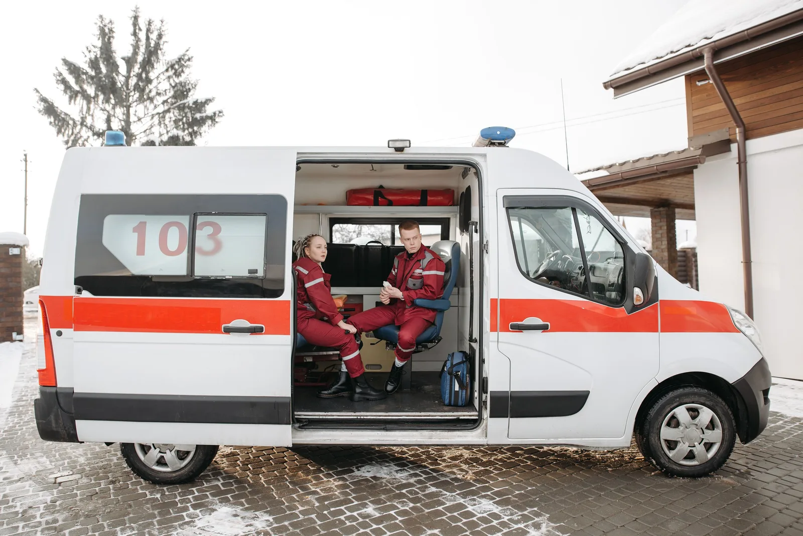 Two paramedics sitting in an ambulance parked outside on a snowy day. Photo by Pavel Danilyuk on Pexels