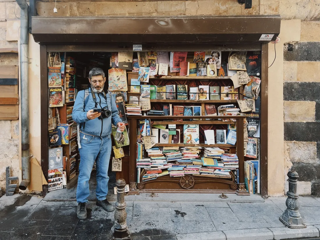 A quaint street bookstore stocked with diverse titles and a photographer capturing the moment. Photo by Mehmet Turgut  Kirkgoz on Pexels