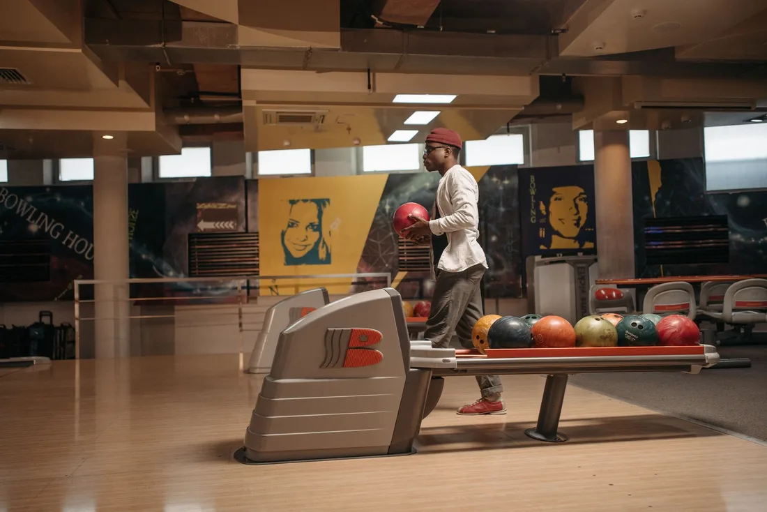 A man getting ready to bowl inside a stylish, modern bowling alley with colorful balls. Photo by Pavel Danilyuk on Pexels