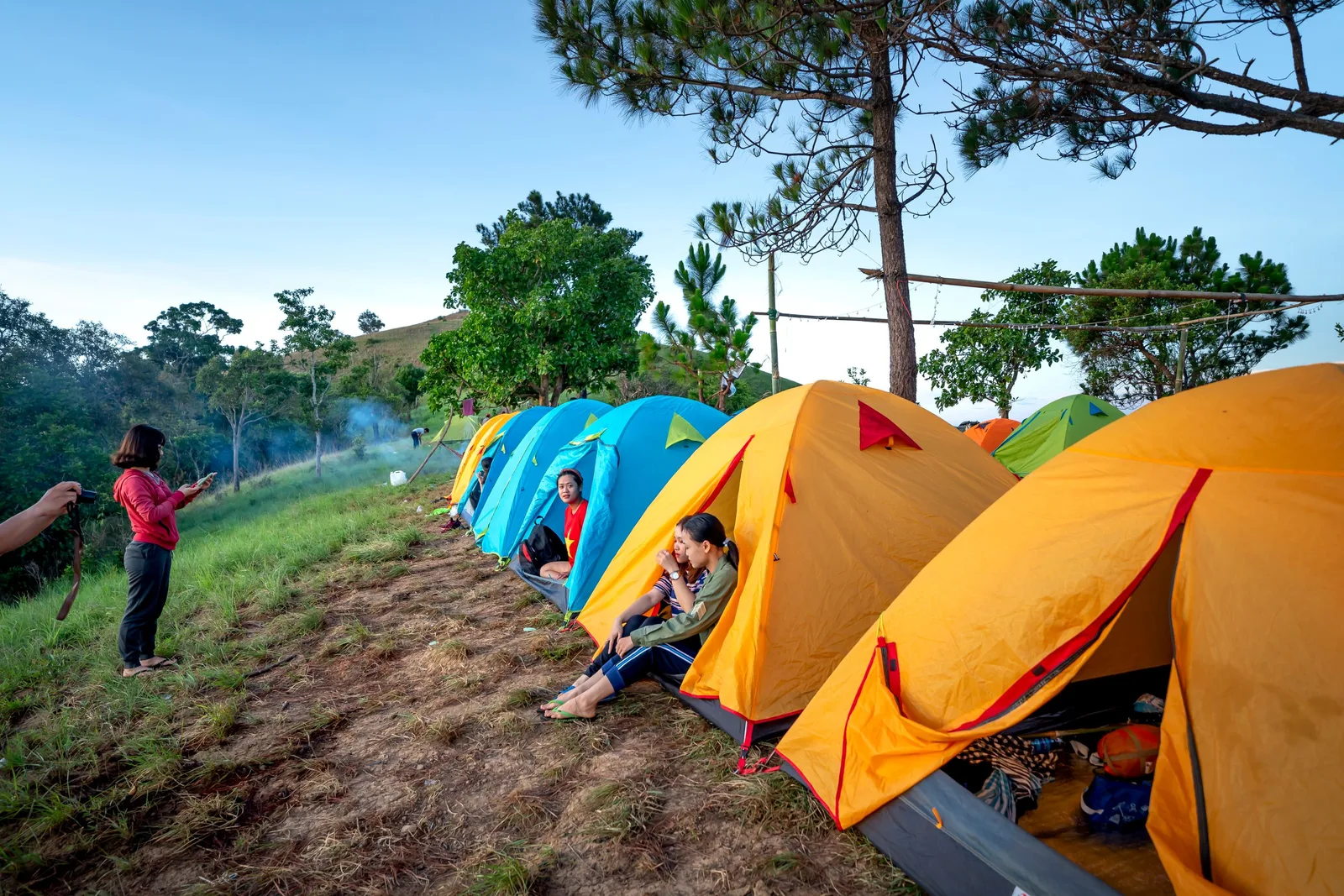 Colorful tents pitched on a sunny forest campsite with trees. Photo by Quang Nguyen Vinh on Pexels