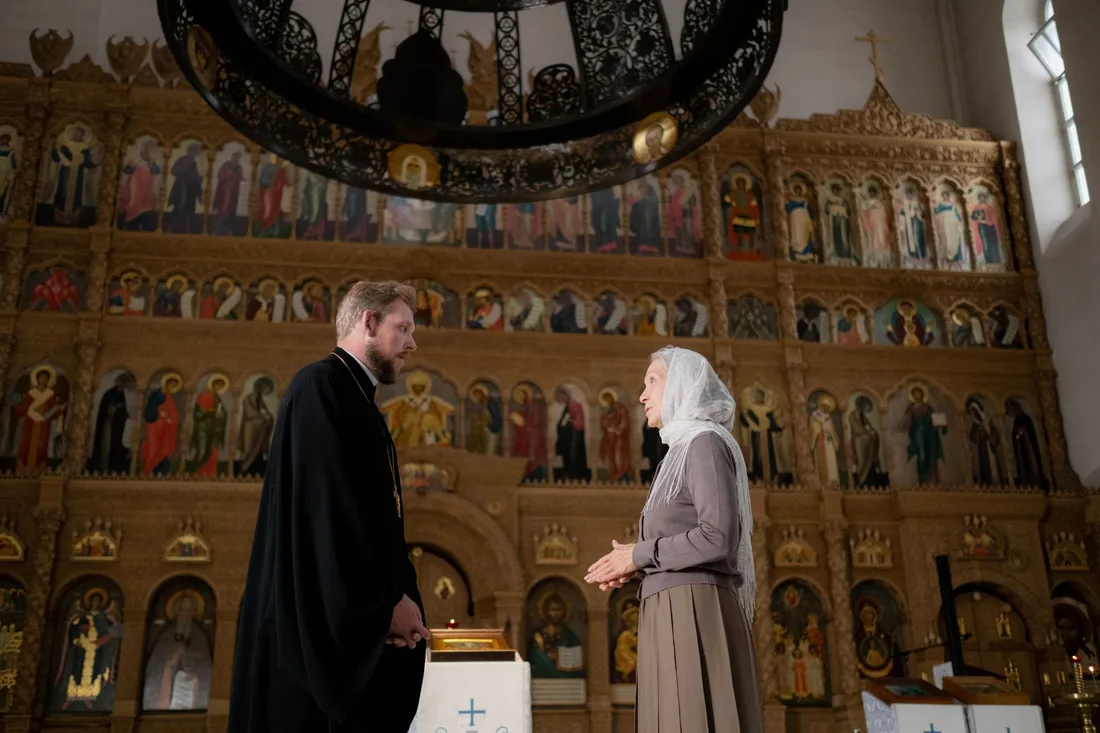 A priest and a parishioner engage in conversation inside an ornate Orthodox church. Photo by Ron Lach on Pexels