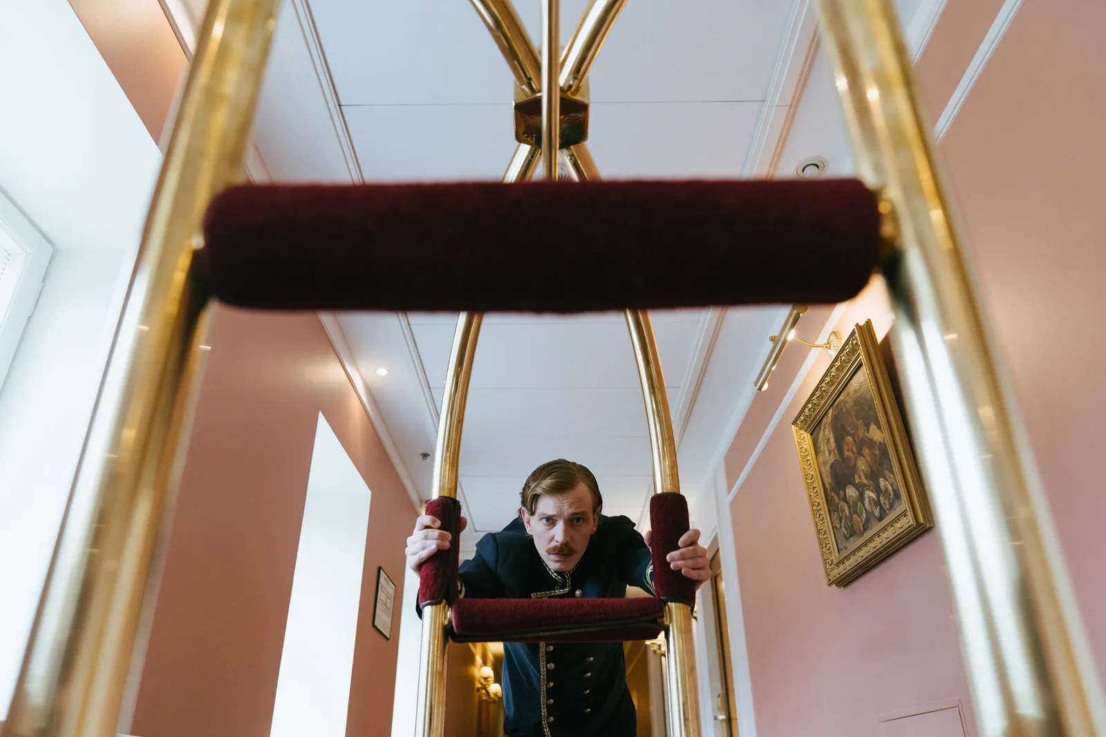 Hotel staff member in uniform pushing a luggage trolley through a corridor. Photo by cottonbro studio on Pexels