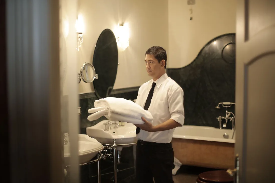 Side view of young male employee holding stack of white towels while standing in bathroom of luxury hotel. Photo by Andrea Piacquadio on Pexels