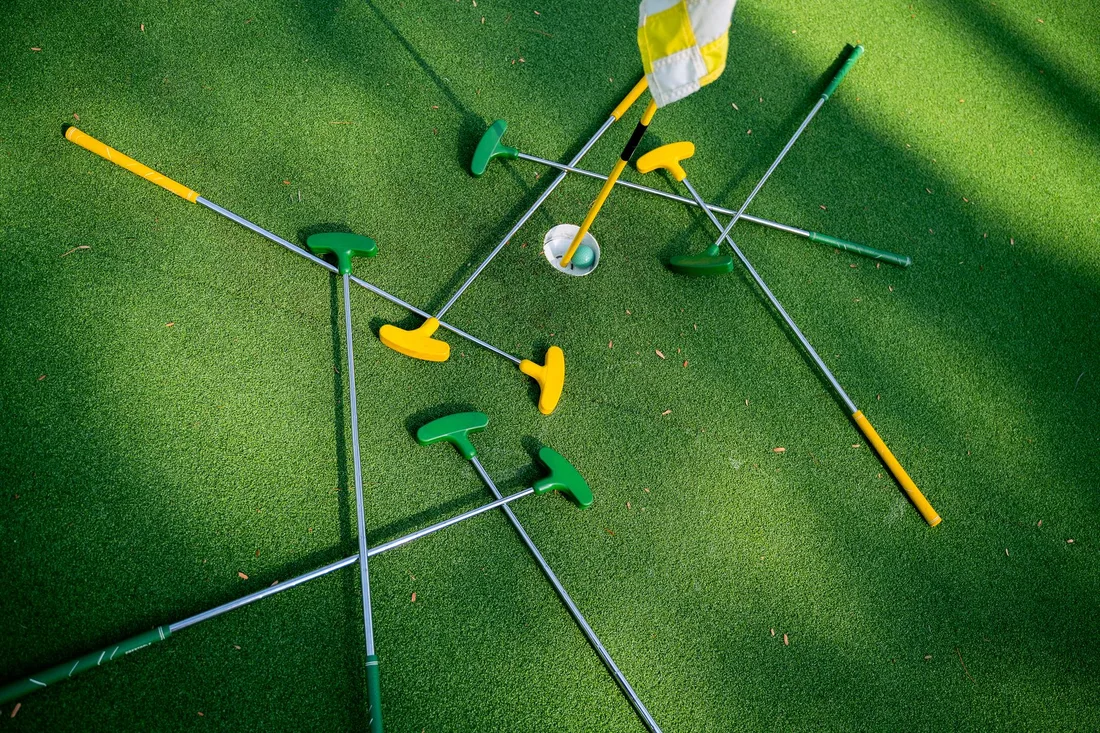Top view of colorful putters scattered around a golf hole on lush green grass. Photo by Anna Tarazevich on Pexels