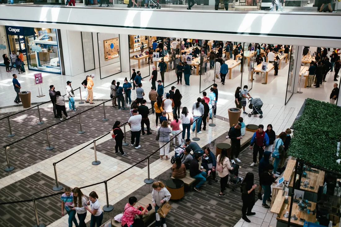 A bustling shopping center with a large crowd queuing inside an Apple Store. Photo by Deane Bayas on Pexels
