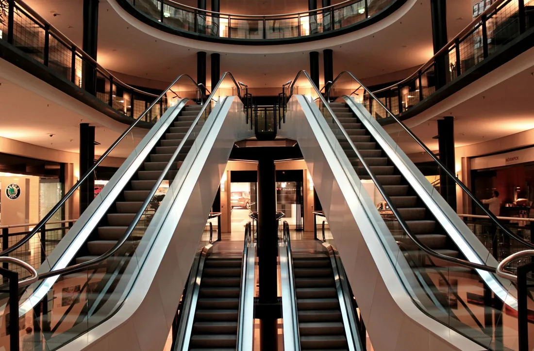 Symmetrical view of escalators in a modern shopping mall interior, showcasing architecture and design. Photo by Pixabay on Pexels
