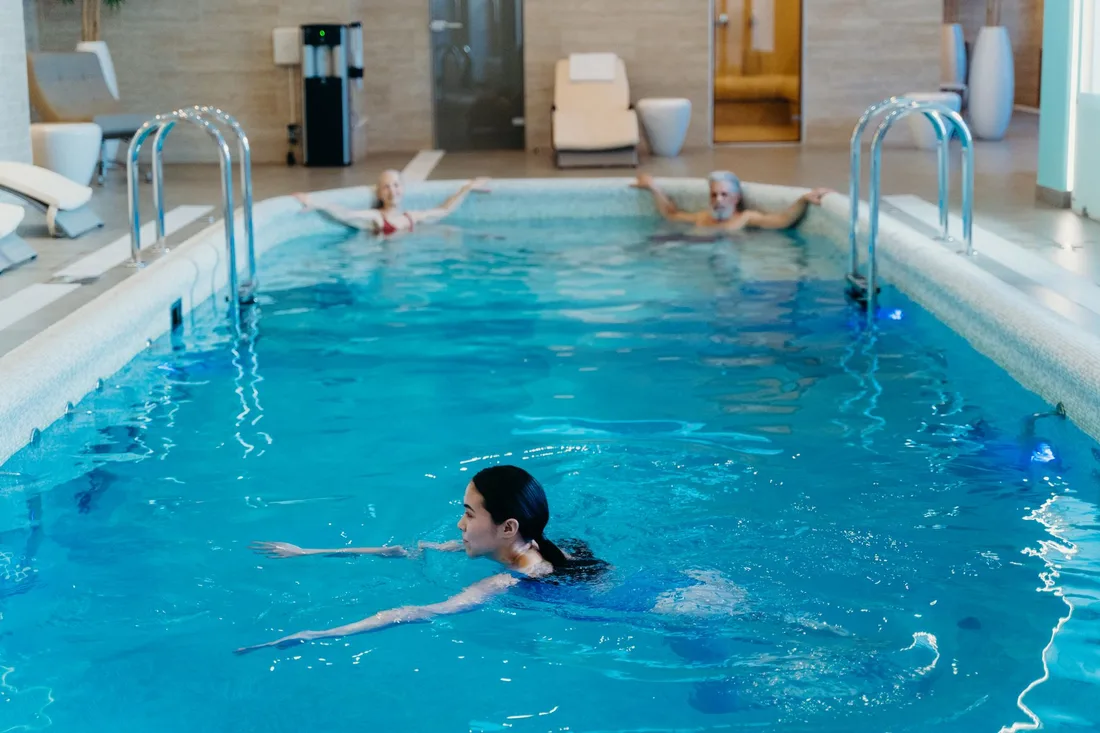 Woman swimming in a bright blue indoor swimming pool. Photo by cottonbro studio on Pexels