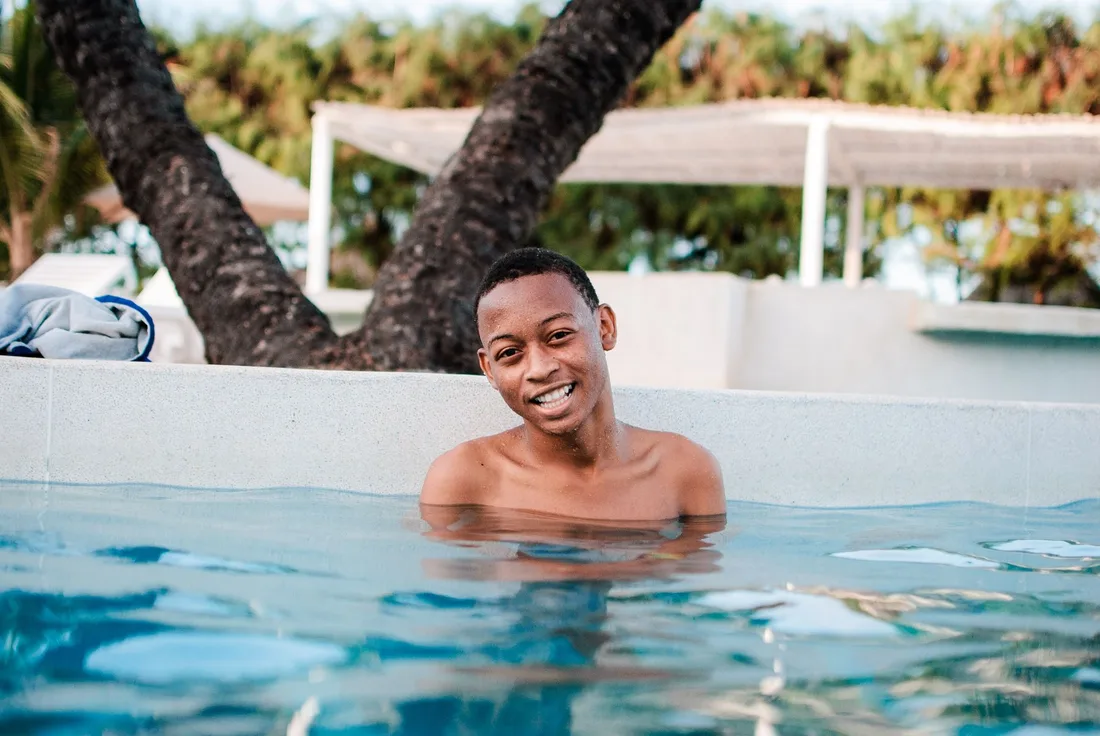 A happy man enjoying a relaxing swim in an outdoor pool during summer. Photo by Mwabonje Ringa on Pexels