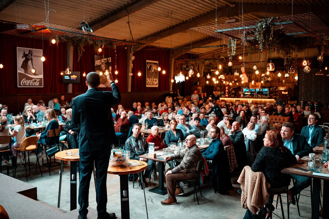 A speaker addressing a large crowd in a vibrant, warmly-lit indoor venue. Photo by Jitte Davidson on Pexels