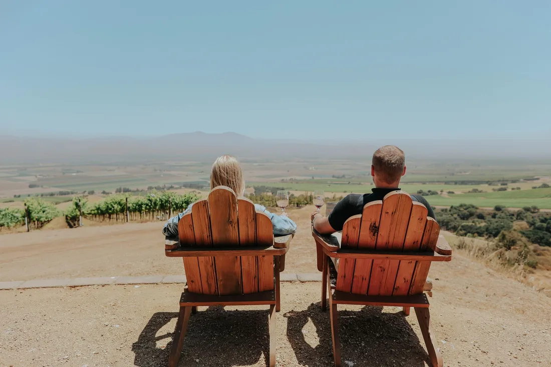 Couple relaxing in chairs overlooking a vineyard landscape. Photo by ArtHouse Studio on Pexels