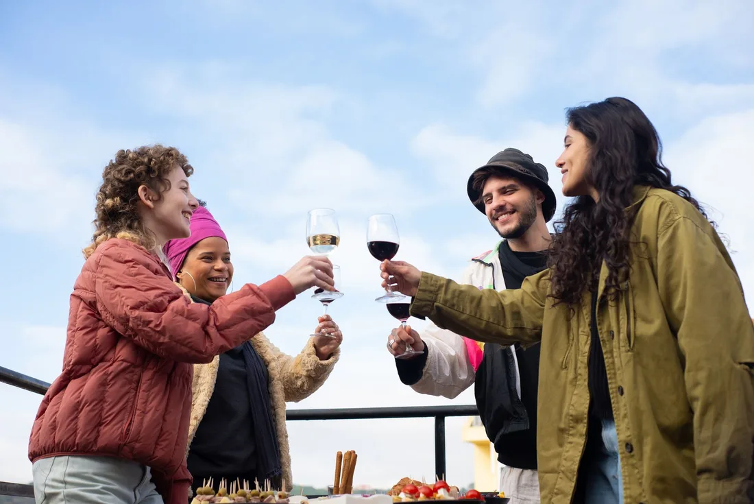 Friends toasting with wine glasses outdoors under a blue sky. Photo by Kampus Production on Pexels