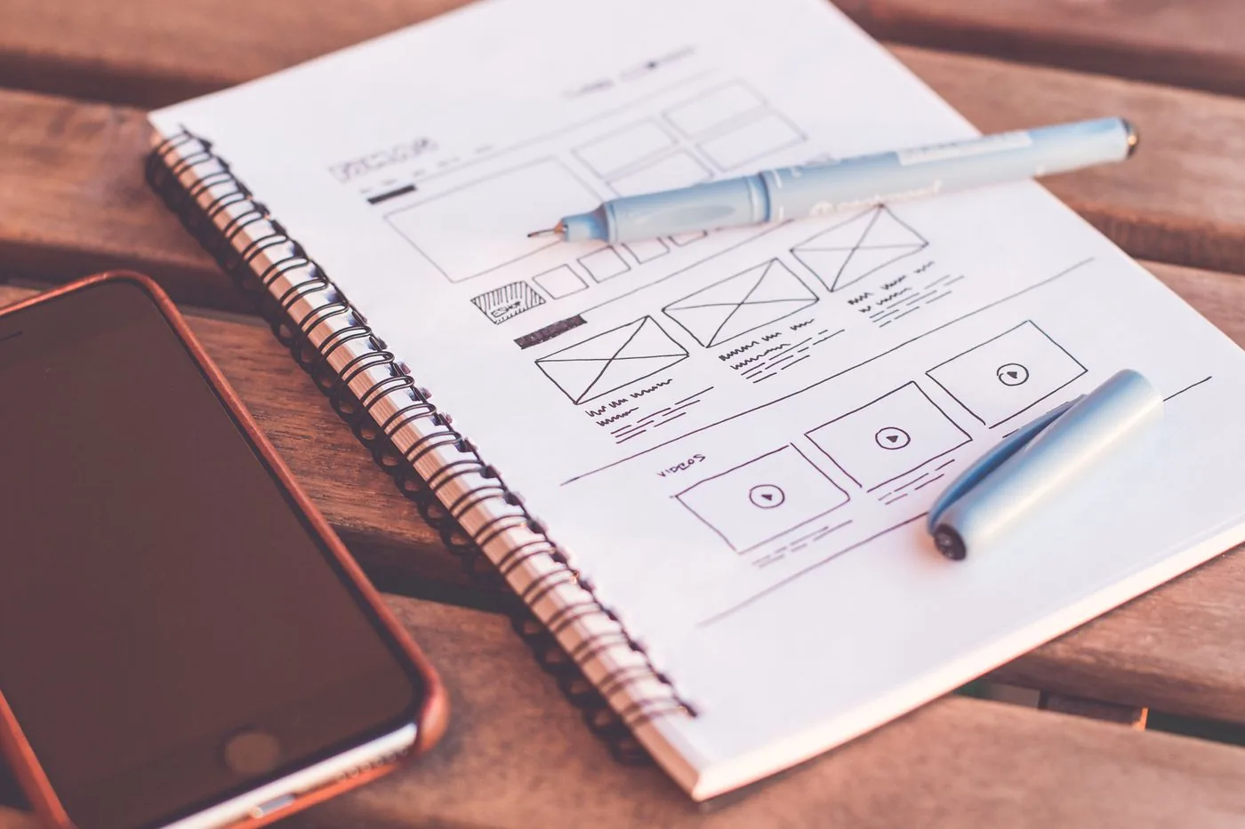 Web wireframes sketched in a notebook with mobile device