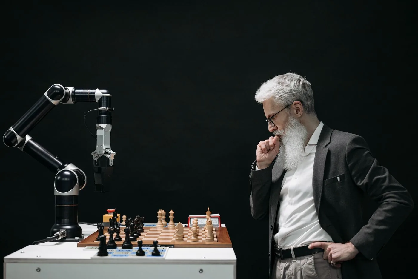 Person facing a robot arm over chess representing AI competitive strategy. Photo by Pavel Danilyuk on Pexels